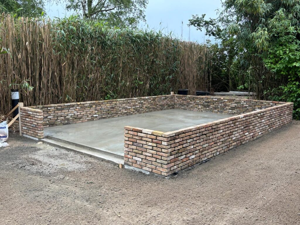Betonnen fundatie met gevlinderde vloer met opgemetselde muren. Nieuwbouw schuur